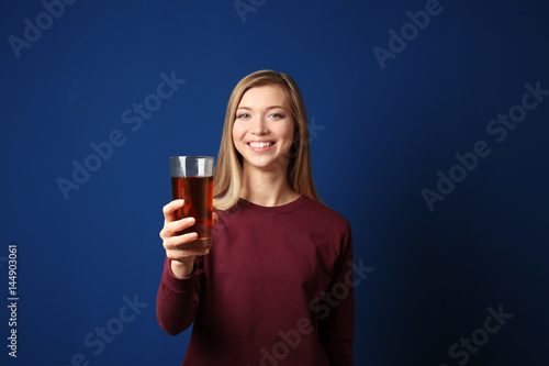 Beautiful young woman with glass of fresh juice on dark blue background