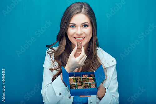Happy young woman eating chocolate candies.