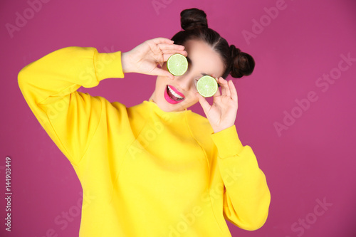 Beautiful young woman with lime on color background