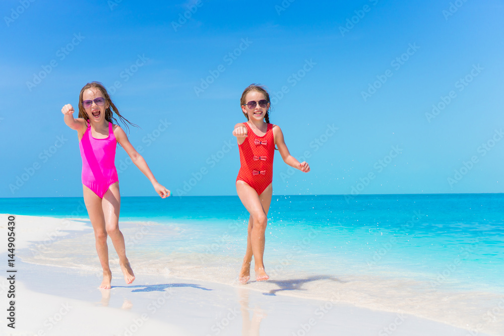 Little girls having fun at tropical beach playing together at shallow water Little girls having fun at tropical beach playing together at shallow water