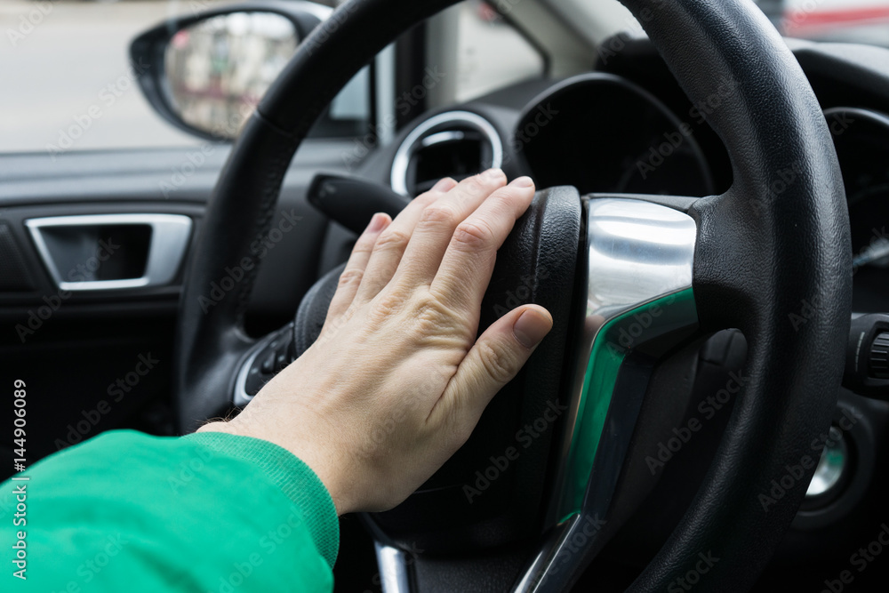 Nervous man driver pushing car horn , close up view of hand on the steering wheel