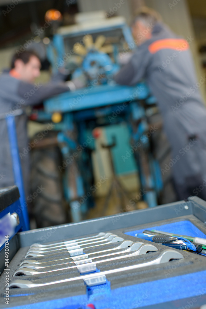 Closeup of set of spanners, mechanics in background Closeup of set of spanners, mechanics in background