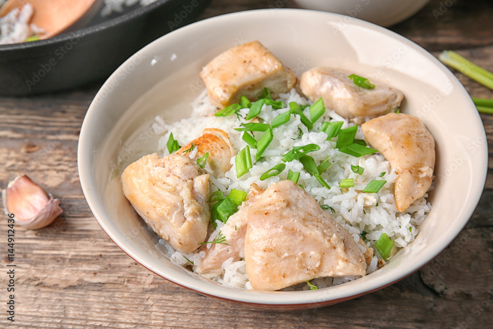 Plate with tasty chicken and rice on wooden table