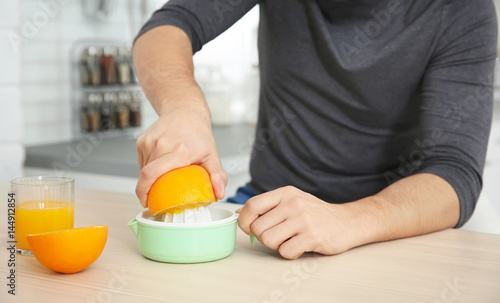 Young man making orange fresh on kitchen