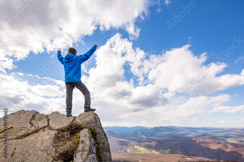 Fototapeta Naklejka Na Ścianę i Meble -  A happy man is standing on the summit above the horizon, beautiful sunny day.