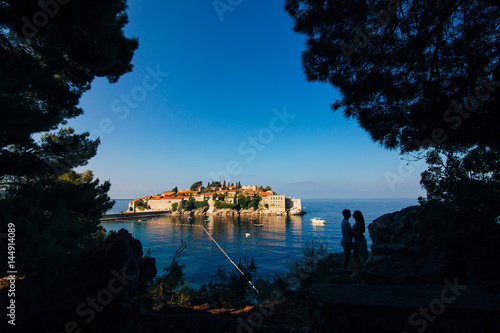 Fototapeta Naklejka Na Ścianę i Meble -  Silhouettes of couples near Sveti Stefan island in Montenegro