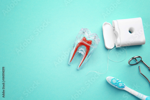 Toothbrush, plastic tooth mockup, dental instruments and floss on color background