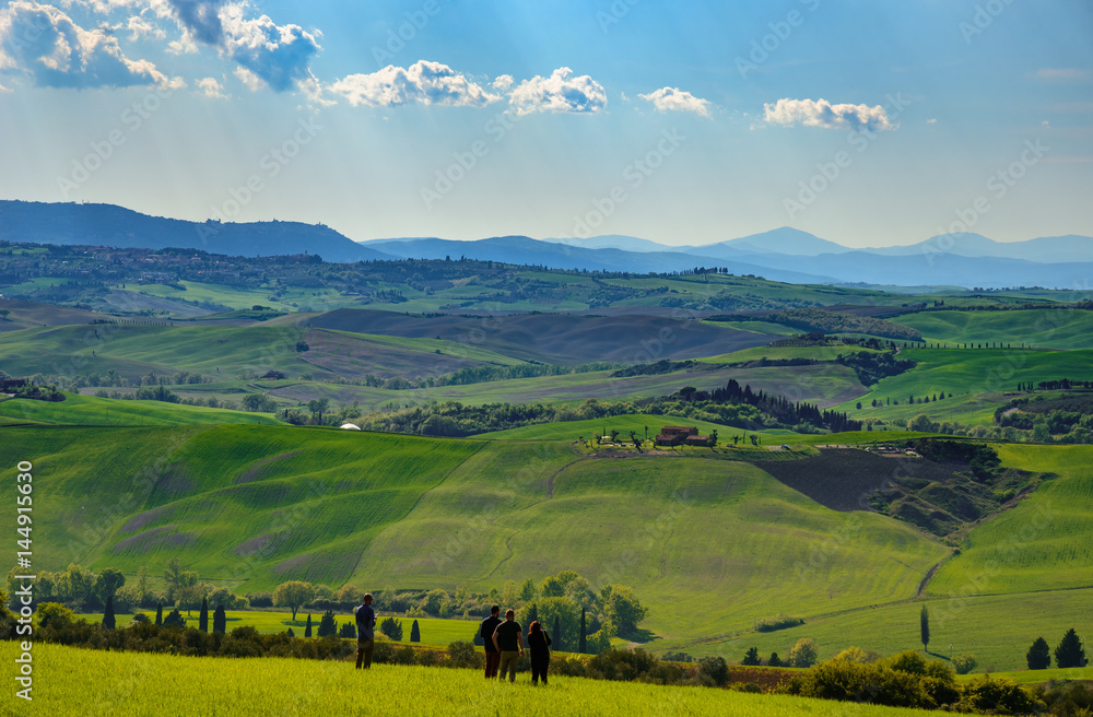 Obraz premium View of Tuscany countryside in spring with a group of tourists who admire the panorama.
