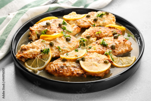 Plate with tasty Italian chicken piccata on table photo