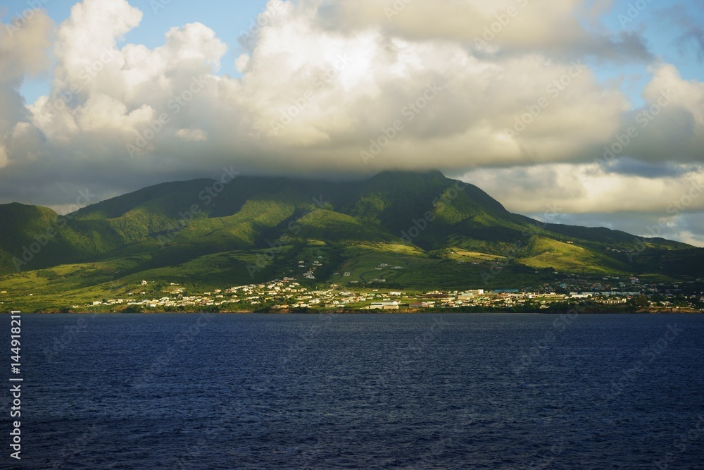 Saint Kitts Island landscape - distant view from water of a hill slope with sun and shade patches