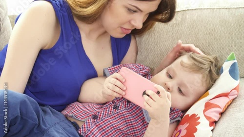 Young bretty mother watching cartoons on the smartphone with her son closeup photo