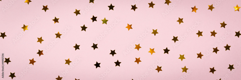 Golden star sprinkles on pink. Festive holiday background. Celebration concept Golden star sprinkles on pink. Festive holiday background. Celebration concept