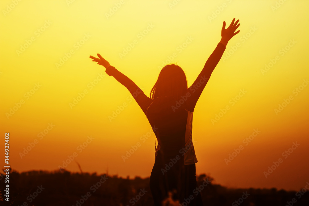 Happy woman raised hands up on the sky at sunset Happy woman raised hands up on the sky at sunset