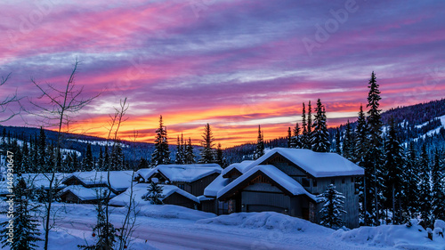 Red and Orange sky at a sunrise over the snow covered houses in the alpine village of Sun Peaks in the Shuswap Highlands of central British Columbia, Canada