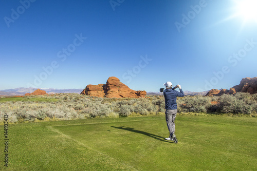 Rear view of a man playing golf on a Sunny day on a beautiful desert golf course in the Southwestern United states.