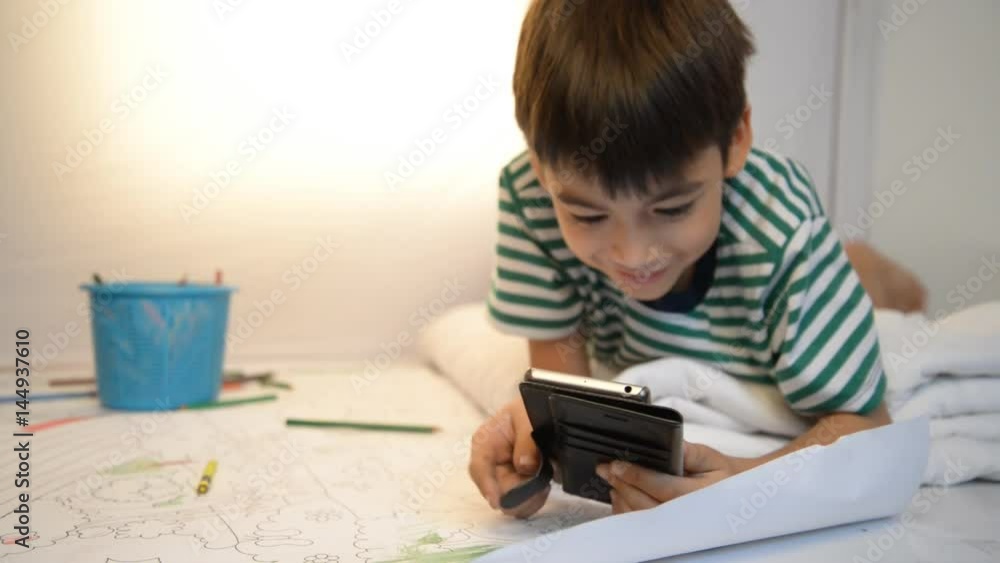 Little boy playing game on mobile with smile in the room Stock video Little boy playing game on mobile with smile in the room Stock video