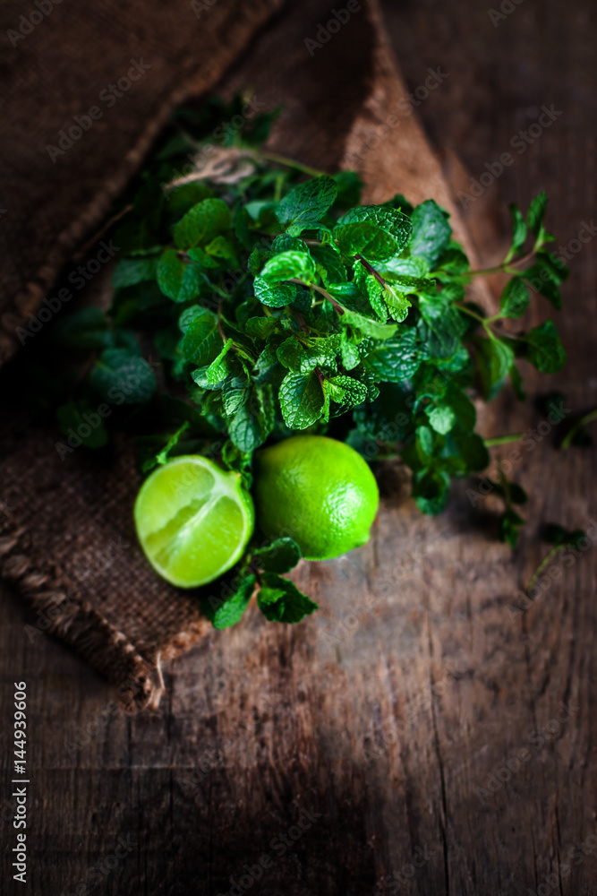 Fototapeta Fresh mint leaves herb and lime on dark wooden table. Top view with copy space