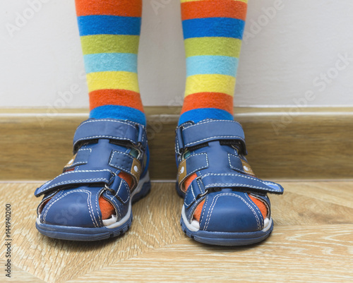 Little boy feet in sandals and striped bright socks. Summer children's shoes.
