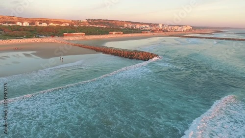 Aerial videoin motion during sunset in the Atlantic Ocean in Costa da Caparica, Lisbon, Portugal.