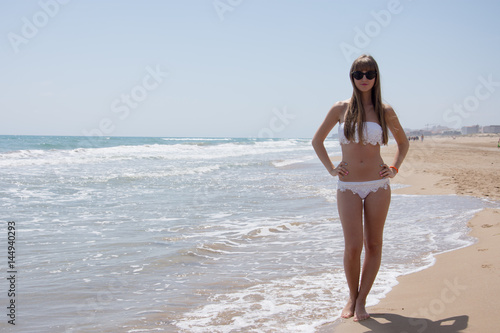 Young woman in bikini at the beach of the sea on a sunny day