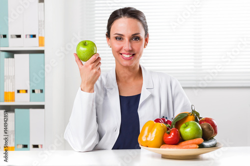 Female nutritionist holding a green apple