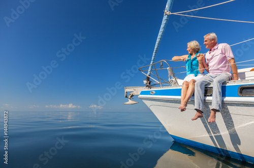 Happy Senior Couple Sitting on the Side of a Sail Boat
