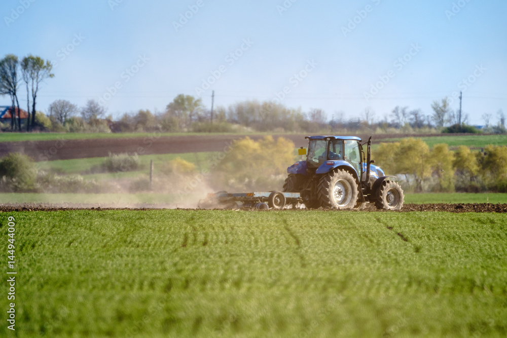 Fototapeta premium Tractor harrowing the land