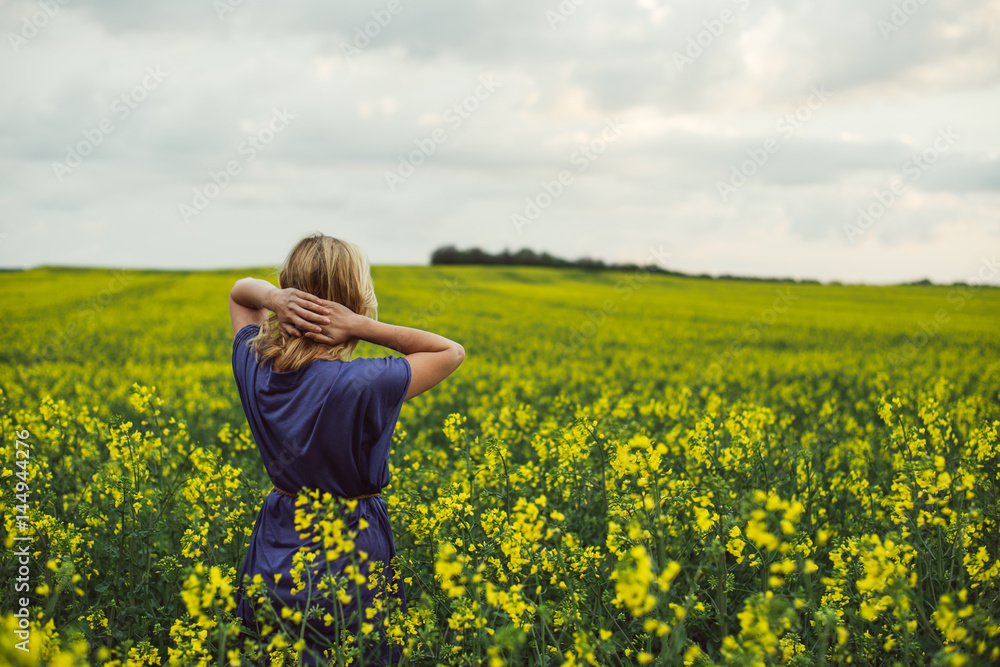 Carefree woman standing in rapeseed field, watching sunset. Carefree woman standing in rapeseed field, watching sunset.
