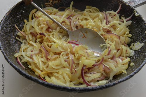 Fried colorful onion in a frying pan