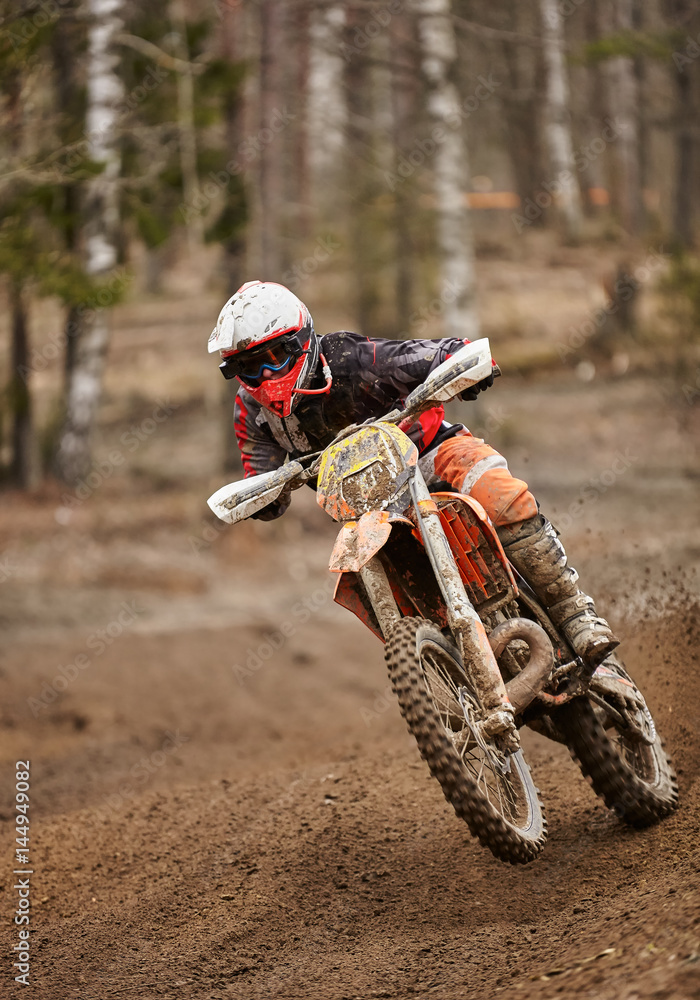 Motocross enduro driver in action accelerating the motorbike on the race track. Motocross enduro driver in action accelerating the motorbike on the race track.