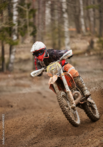 Motocross enduro driver in action accelerating the motorbike on the race track.