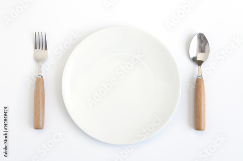 A white plate with fork and spoon on white background.