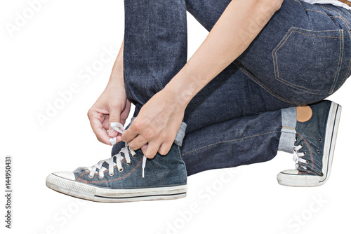 Tie his shoes Retro Canvas High Top Sneakers and Regular Fit Straight Leg Jeans isolated on white background, selective focus (detailed close-up shot)