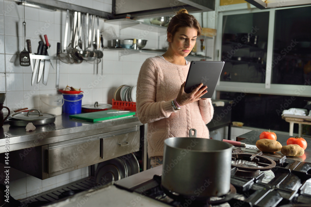 Young woman reading a recipe on a digital tablet in the kitchen Young woman reading a recipe on a digital tablet in the kitchen