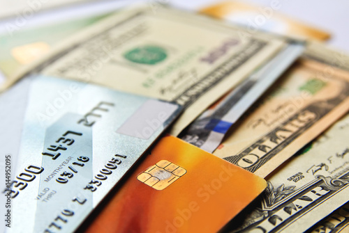 Stack of credit cards and american dollars cash, close-up view.