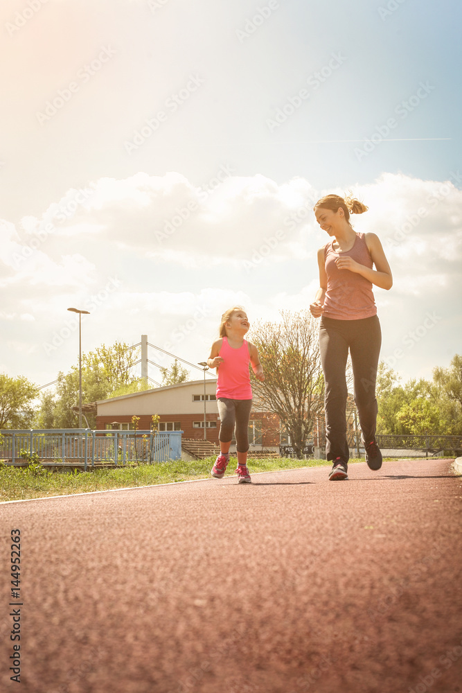 Fototapeta premium Caucasian mother and daughter jogging outdoors.