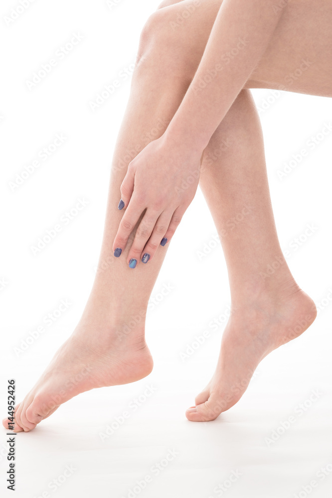Female legs and hands, over white background. Beautiful female legs after depilation.
