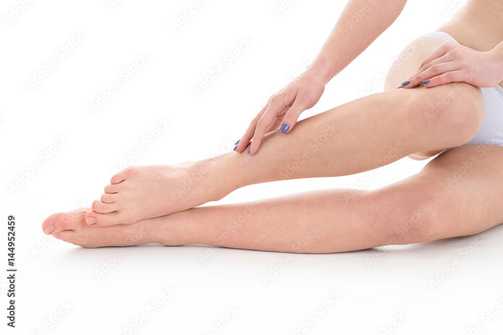 young woman model touching her tanned fit legs over white background young woman model touching her tanned fit legs over white background