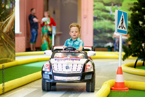 Little boy driving a toy car on a traffic playground