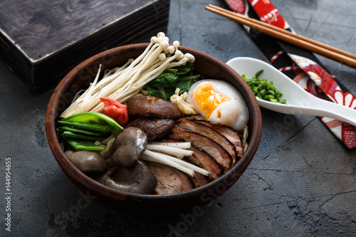 Ramen noodles bowl with egg, enoki, shiitake mushrooms, duck and onion photo