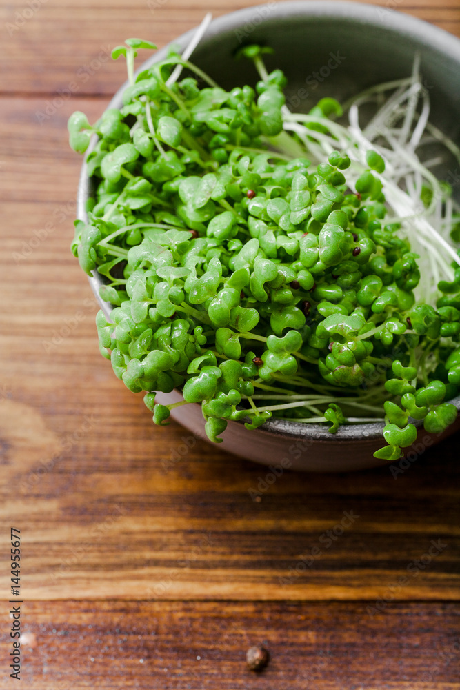 Mustard microgreen salad in metallic bowl on wooden background Mustard microgreen salad in metallic bowl on wooden background