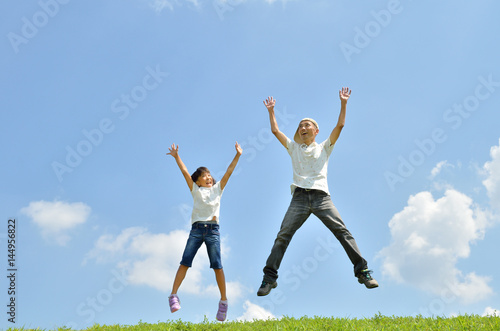 青空でジャンプする親子（夏） © hanapon1002