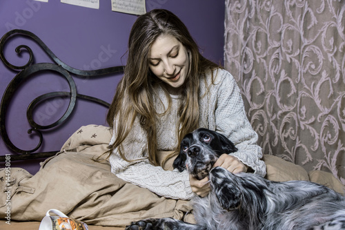 A girl and her dog waking up in bedroom