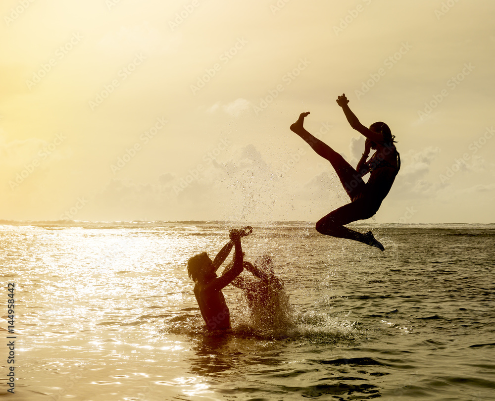 Silhouette of young woman jumping out of ocean