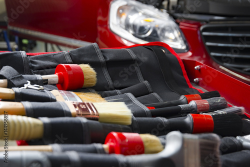 Complect of brushes for cleaning car detailing in front of red car