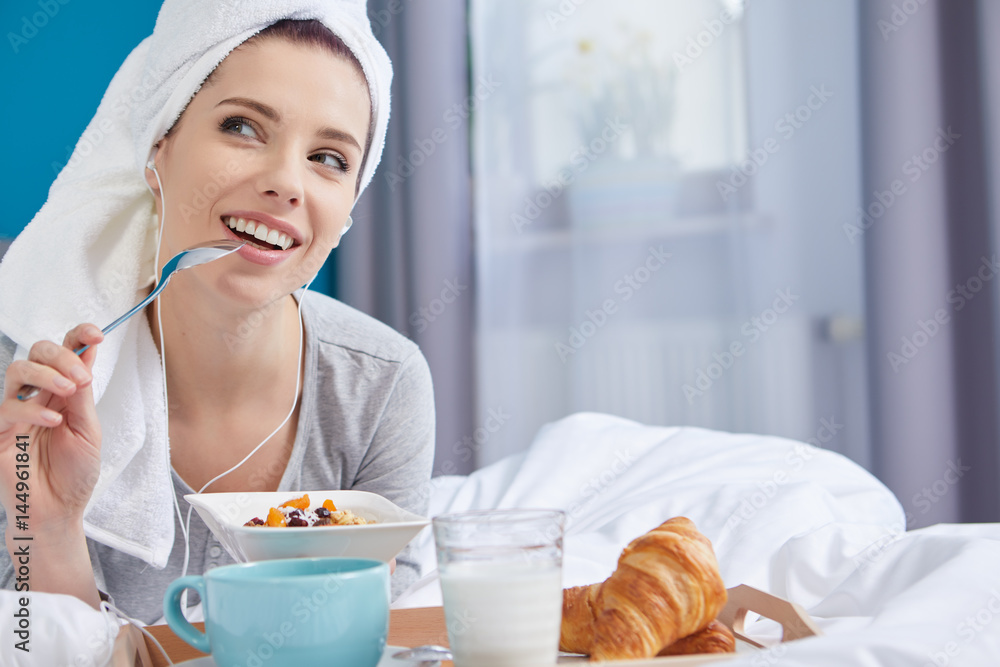 Portrait of a happy smiling european woman eating a healthy breakfast of fruit and yoghurt in bed. Portrait of a happy smiling european woman eating a healthy breakfast of fruit and yoghurt in bed.
