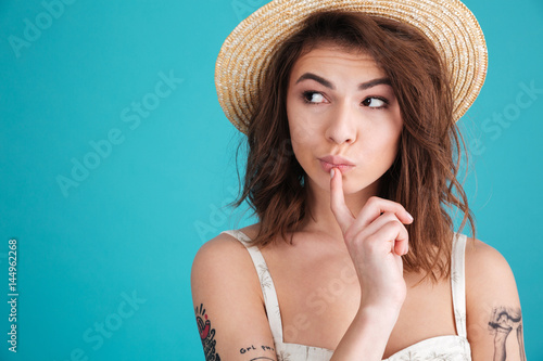 Thoughtful young woman in straw hat wondering and looking away photo