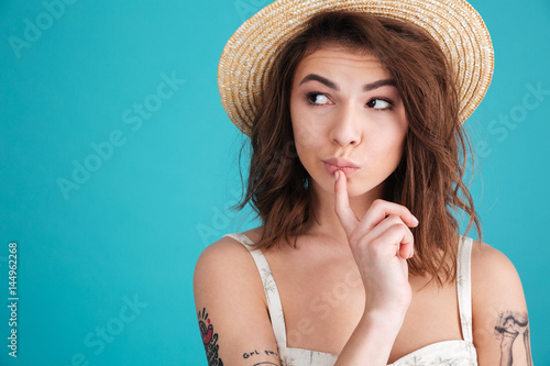 Fotografie Thoughtful young woman in straw hat wondering and looking away
