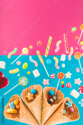 Close-up top view of waffle cones and mix of various sweets on bright background