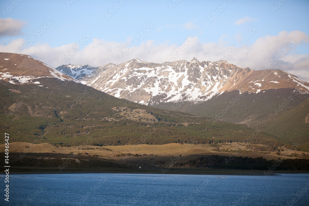 Tierra del Fuego,  landscape of snowy and wooded mountains and ocean